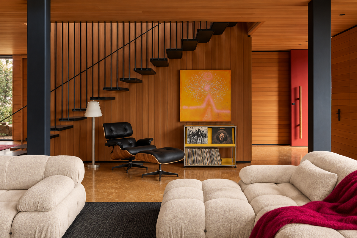 Wood-panelled living room with a cream modular sofa and a black leather lounge chair